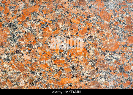 Background e texture - variegato di superficie levigata lastra di granito con spruzzi di colore arancione Foto Stock