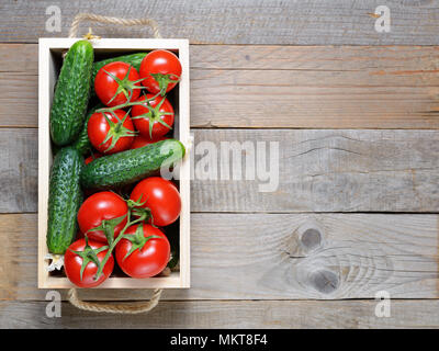 Pomodori e cetrioli in cassetta di legno vista superiore Foto Stock