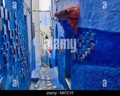 Apertura stretta tra le pareti blu di un vecchio edificio, decorato con piastrelle di ceramica, Chefchaouen, Marocco. Foto Stock