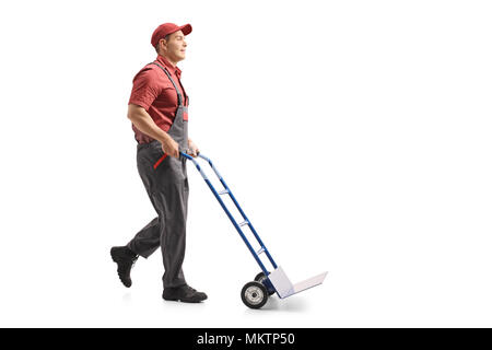Lunghezza piena ripresa di profilo di un mover spingendo una mano Vuota carrello isolato su sfondo bianco Foto Stock