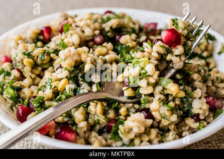 Insalata di grano con melograno in bianco ciotola. cibo organico Foto Stock