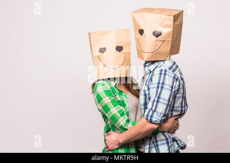 Amore giovane che coprono i loro volti con sacchetto di carta su sfondo bianco Foto Stock