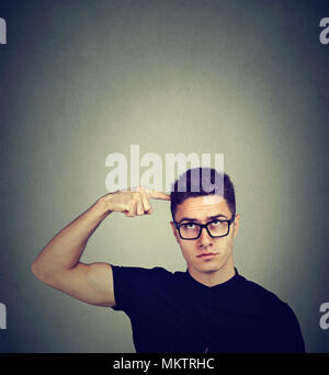 Pensando perplesso uomo che guarda verso l'alto isolato sul muro grigio Sfondo. Riflessivo guy graffiare la testa per risolvere un problema Foto Stock