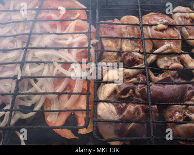 Shish kebab e pomodori a pezzi con le cipolle sono arrostiti sulla griglia, fumo. Foto Stock