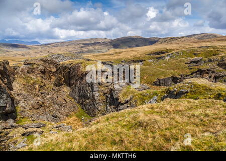 Guardando oltre il crollo del tetto della cava Rhosydd Twll Est verso vette di Snowdon Foto Stock