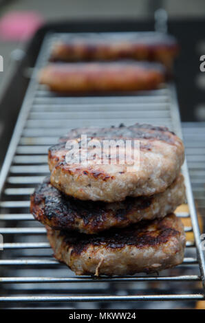 Gli hamburger e salsicce grigliare su un barbecue Foto Stock