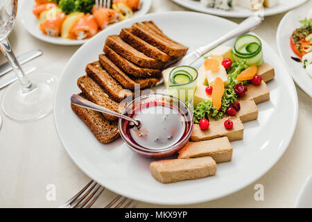 I piatti serviti al tavolo per le vacanze. Posate e cibo su tovaglie bianche nel ristorante. La progettazione di un banchetto di festa. Cibo di lusso per ospiti e visitatori. Foto Stock