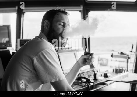 Navigazione Deck officer fuma una borra sul ponte di navigazione di yacht Foto Stock