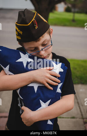 Un ragazzo giovane azienda ripiegata di bandiera americana. Foto Stock