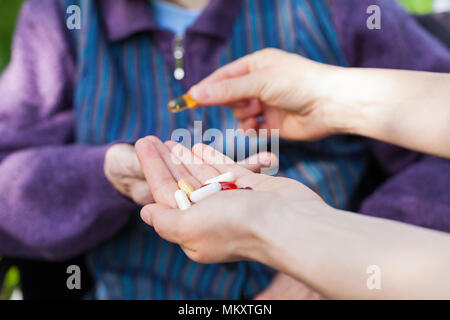 Anziani malati donna ricevere pillole da infermiera all'aperto, medico iscritto prescrizione medica in background Foto Stock