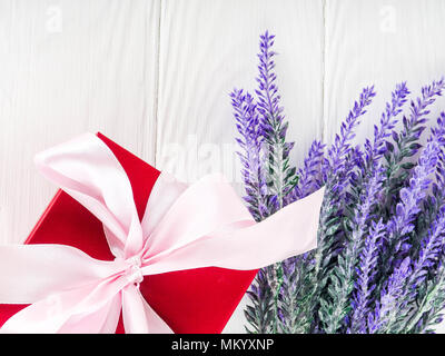 Piccola scatola regalo decorata con nastro e fiore, splendida e romantica scatola regalo su legno. Foto Stock