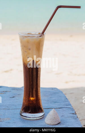 Caffè ghiacciato sul tavolo di legno con lo sfondo del mare Foto Stock