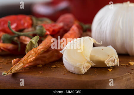 Super piccante calda secca leggere peperoni e aglio sul tagliere di legno. Foto Stock