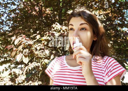 Ragazza gocciolamenti naso chiuso da allergia. Donna con Apparato Respiratorio Spray per naso in fioritura primaverile. Ritratto di una donna con problemi respiratori da un Foto Stock