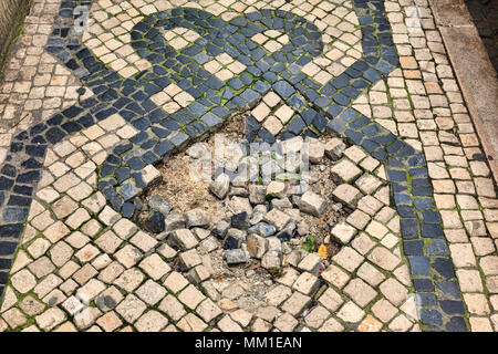 Una sezione della pavimentazione portoghese a Lisbona, Portogallo, con un pot foro in esso. Foto Stock
