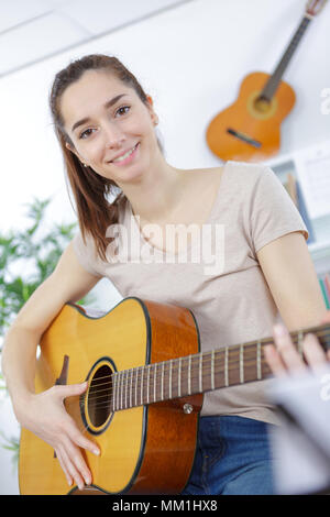 Bella ragazza adolescente in maglietta e jeans strappati a suonare la chitarra Foto Stock