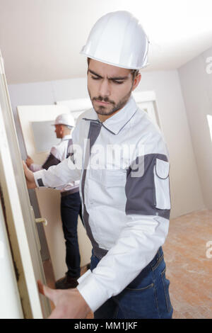 Giovani builder montaggio tavole di isolamento nel tetto della nuova casa Foto Stock