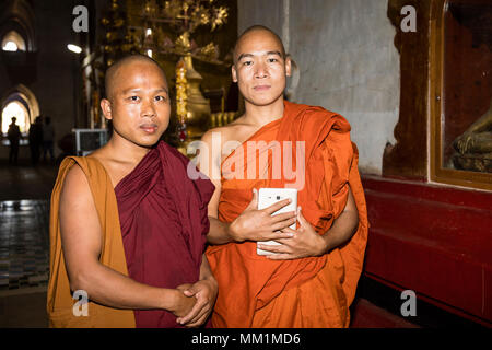 Bagan, Myanmar, Dicembre 29, 2017: Ritratto di due monaci buddisti nella Pagoda di Ananda in Bagan. Un monaco trattiene un tablet in mano. Foto Stock