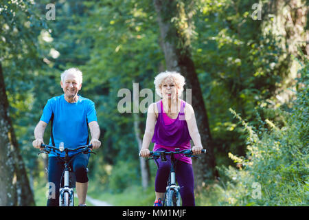 Felice e attivo coppia senior equitazione biciclette all'aperto nel parco Foto Stock