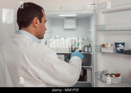 Tecnico di laboratorio la memorizzazione dei campioni di sangue in frigo Foto Stock