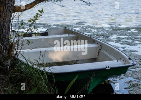 Una barca da pesca ormeggiate alla riva del lago. Vecchi pescatori della barca preparata per la pesca sui laghi. Stagione della primavera. Foto Stock