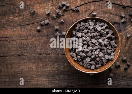 Dark cholocale bocconcini in una ciotola contro scuri in legno rustico sfondo Foto Stock