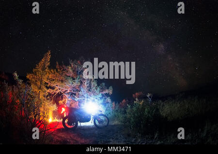 Accampamento notturno fuoco con moto enduro da soli viaggiatori steppa del paesaggio su uno sfondo di stelle e la via lattea montagne di Altai in Siberia Russia Foto Stock