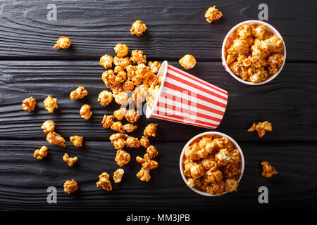 Scatole con caramello wweet popcorn, sfondo nero, snack per il cinema closeup. Parte superiore orizzontale vista da sopra Foto Stock