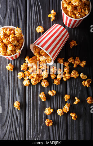 Scatole con caramello wweet popcorn, sfondo nero, snack per il cinema closeup. Verticale in alto vista da sopra Foto Stock