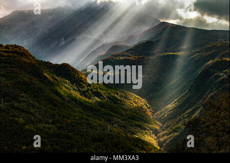 I raggi del sole filtrano attraverso le nuvole di una valle montuosa, il Parco Nazionale del Gran Sasso e dei Monti della Laga, Abruzzo, Italia Foto Stock