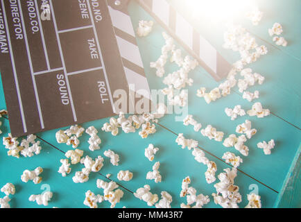 Popcorn e clapperboard colorato su sfondo blu Foto Stock