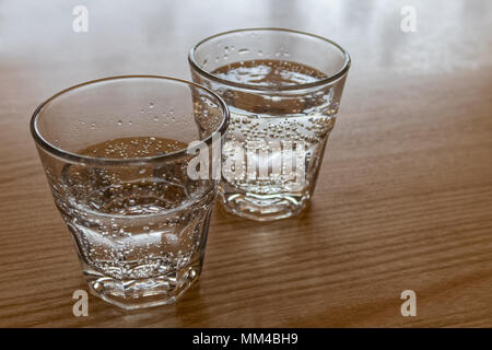 Due appena spillata bicchieri di acqua frizzante isolati su legno. Foto Stock