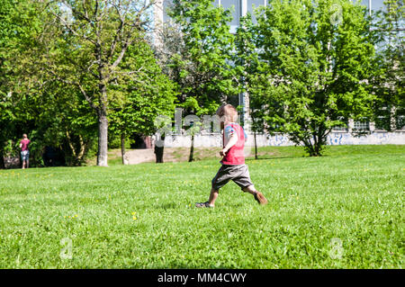 Praga Repubblica Ceca, 28 aprile 2018 little boy in trick e pantaloncini in esecuzione nel parco su erba in background di alberi Foto Stock