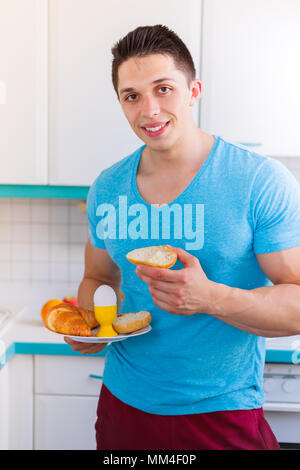 Mangiare la prima colazione giovane uomo in cucina formato ritratto sorridente mattina mangiare Foto Stock