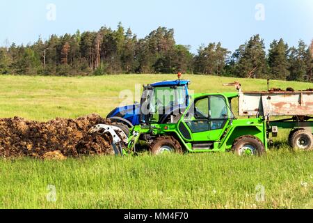 Il concime naturale agro bio la fecondazione. Concime di carico sul trattore. Il paesaggio agricolo nella Repubblica Ceca Foto Stock