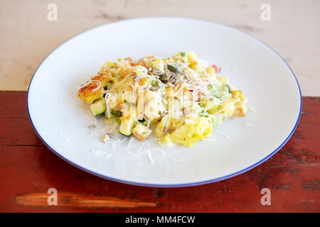 Primo piano della piastra bianca con le patate e le verdure sul tavolo di legno Foto Stock