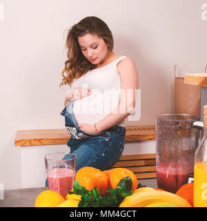 Bella donna incinta di accarezzare il suo stomaco con frutti in primo piano Foto Stock