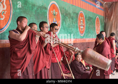 Monaci Tibetani giocando a lungo le corna al Jinganqumo festival di purificazione in Dege, Sichuan, in Cina Foto Stock