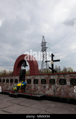 Memoriale per i liquidatori alla centrale nucleare di Cernobyl vicino nuovo confinamento sicuro (NSC) nuovo sarcofago oltre danneggiato reattore 4 in background Foto Stock