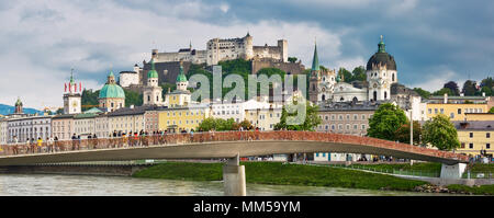 Salisburgo, Austria - 4 Maggio 2018: vista alla fortezza di Hohensalzburg e Staatsbruecke ponte attraverso il fiume Salzach su una serata primaverile con molte persone w Foto Stock