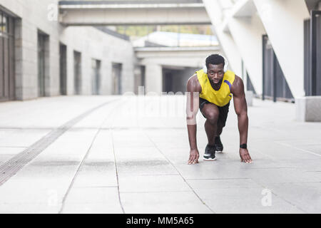 Afro-uomo in esecuzione di avviare pongono sulla strada della citta'. Colpo all'aperto, la mattina. Primavera o estate Foto Stock