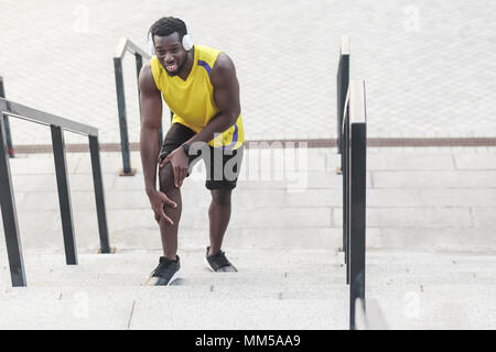 Closeup ritratto uomo infelice. Problemi con le giunzioni in atleti dopo il jogging. Colpo all'aperto, la mattina. Primavera o estate Foto Stock