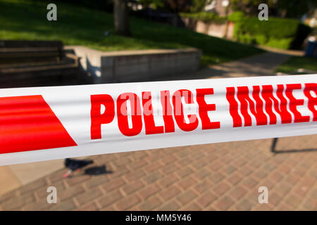 Cordone interno nastro barriera posta dalla polizia o scena del crimine officer / Officer presso il sito di un accoltellato dove qualcuno è stato pugnalato con un coltello. Regno Unito Foto Stock