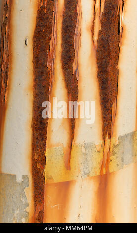 Un primo piano di una parte esterna di un tubo metallico con alcune linee verticali e incrinato la vecchia vernice. Foto Stock