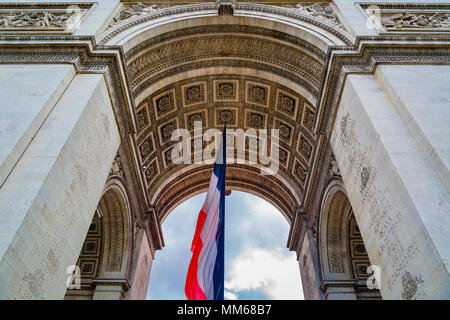 Tri-Color bandiera francese volare al di sotto di Arc de Triomphe, Parigi, Francia Foto Stock