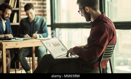 Direttore commerciale di lavorare con grafici finanziari sul laptop Foto Stock