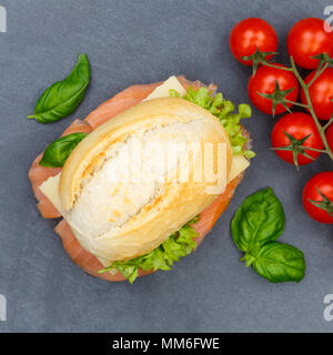 Baguette sandwich con salmone affumicato pesce dal quadrato sopra ardesia vista superiore Foto Stock