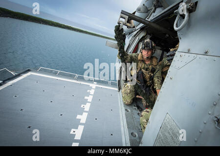 Un'eliminazione degli ordigni esplosivi tecnico, assegnato per l'eliminazione degli ordigni esplosivi unità mobile (EODMU) 5, si prepara a distribuire un fast-corda da un MH-60S Seahawk, appartenenti alla "Isola" dei Cavalieri del Mare in elicottero Combat Squadron 25 (HSC-25), sulla USNS 2 Lt. John P. Bobo (T-AK 3008), durante l'elicottero, visita la scheda, ricerca e sequestro (HVBSS) formazione in Apra Harbor, Guam, Sett. 12, 2017. EODMU 5 conduce il mio contromisure contro-improvvisato dispositivo esplosivo operazioni, rende sicuro rischi di esplosione e disarma underwater esplosivi come mine. (U.S. Navy combattere la fotocamera in massa Foto Stock