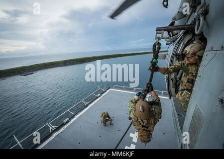 I marinai, assegnato per l'eliminazione degli ordigni esplosivi unità mobile (EODMU) 5, fast-corda da un MH-60S Seahawk, appartenenti alla "Isola" dei Cavalieri del Mare in elicottero Combat Squadron 25 (HSC-25), durante un elicottero, visita la scheda, ricerca e sequestro (HVBSS) formazione sulla USNS 2 Lt. John P. Bobo (T-AK 3008) in Apra Harbor, Guam, Sett. 12, 2017. EODMU 5 conduce il mio contromisure contro-improvvisato dispositivo esplosivo operazioni, rende sicuro rischi di esplosione e disarma underwater esplosivi come mine. (U.S. Navy combattere la foto della telecamera tramite la comunicazione di massa Specialist 1a classe Benjamin A. Lewis) Foto Stock