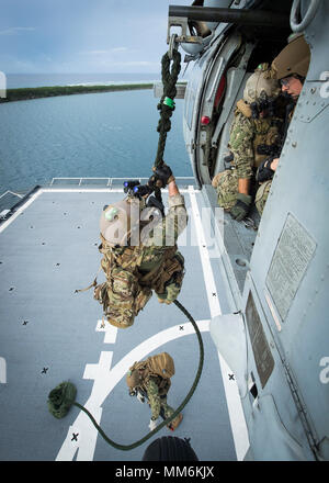 I marinai, assegnato per l'eliminazione degli ordigni esplosivi unità mobile (EODMU) 5, fast-corda da un MH-60S Seahawk, appartenenti alla "Isola" dei Cavalieri del Mare in elicottero Combat Squadron 25 (HSC-25), durante un elicottero, visita la scheda, ricerca e sequestro (HVBSS) formazione sulla USNS 2 Lt. John P. Bobo (T-AK 3008) in Apra Harbor, Guam, Sett. 12, 2017. EODMU 5 conduce il mio contromisure contro-improvvisato dispositivo esplosivo operazioni, rende sicuro rischi di esplosione e disarma underwater esplosivi come mine. (U.S. Navy combattere la foto della telecamera tramite la comunicazione di massa Specialist 1a classe Benjamin A. Lewis) Foto Stock